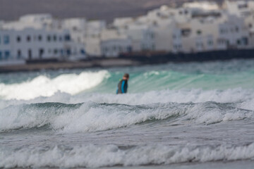 Surfers train in cold water of Atlantic ocean on famous surf Famara beach, Lanzarote, Canary islands, Spain