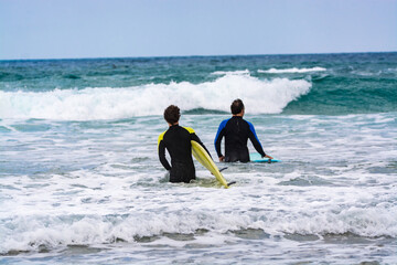 Surfers train in cold water of Atlantic ocean on famous surf Famara beach, Lanzarote, Canary...