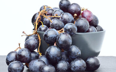 Black grapes on a gray porcelain bowl.