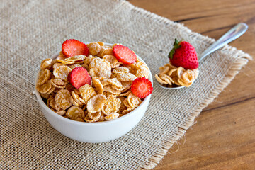 Cornflakes with milk and pieces of strawberry, healthy breakfast.