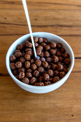 Pouring milk into chocolate cornflakes balls Breakfast with milk and cornflakes.