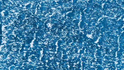 Blue ice surface with scratches and snow