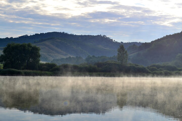 Misty lake in the hills at summer dawn. Arló, Hungary.