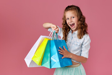cute little caucasian child girl holds shopping bags