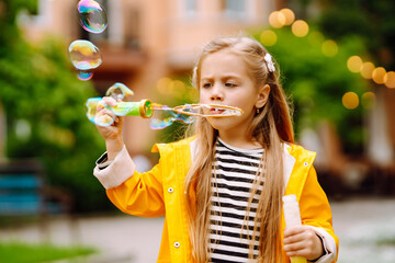 Cute little  girl in the autumn on a walk blowing soap bubbles. Childhood,  active rest, lifestyle...