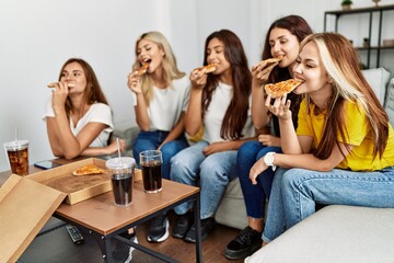 Group of young woman friends smiling happy eating pizza at home.