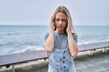 Young caucasian woman outdoors with hand on head for pain in head because stress. suffering...