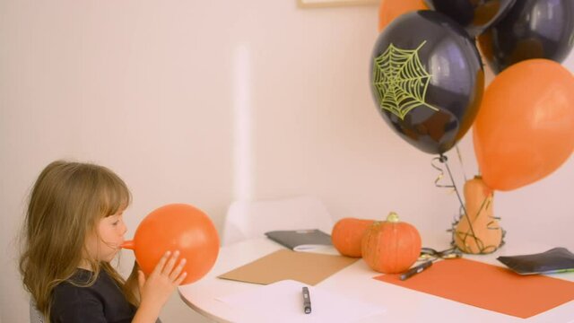 Adorable girl is Inflating Balloons For Halloween