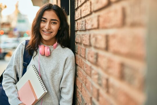 Young middle east student girl smiling happy holding book at the city.