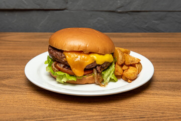Beef burger with melted cheddar cheese, mustard, fried onion, tomato and lettuce and garnish of fried potato wedges