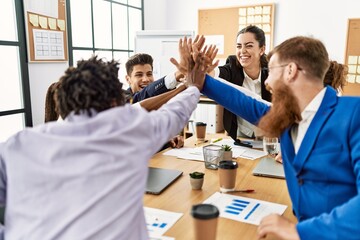 Obraz premium Group of business workers smiling happy celebrating with hands together at the office.