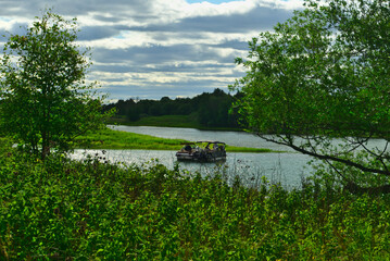 A boat in the river in between the islands of Boucherville national park in Lawrence (Laurent) River, Montreal, QC on a cloudy summer day. The trees and grass on the river banks