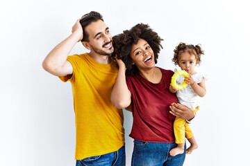 Interracial young family of black mother and hispanic father with daughter smiling confident touching hair with hand up gesture, posing attractive and fashionable