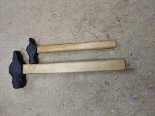 two hammers with wooden handles on the workbench