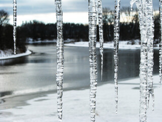 view through window with icicles at frozen river