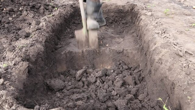 Man digs a deep pit. Digging a pit by shovel.