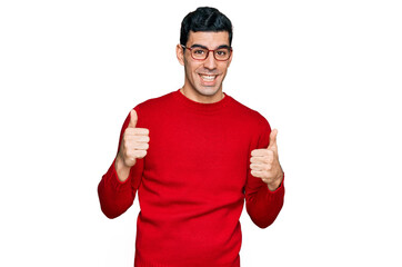 Handsome hispanic man wearing casual clothes and glasses success sign doing positive gesture with...