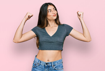 Young beautiful teen girl wearing casual crop top t shirt showing arms muscles smiling proud. fitness concept. - obrazy, fototapety, plakaty