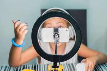 Girl behind a cell phone held with a tripod and a light ring while recording a video for her social networks. Concept with new technologies.