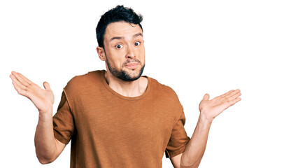 Hispanic man with beard wearing casual t shirt clueless and confused with open arms, no idea and doubtful face.