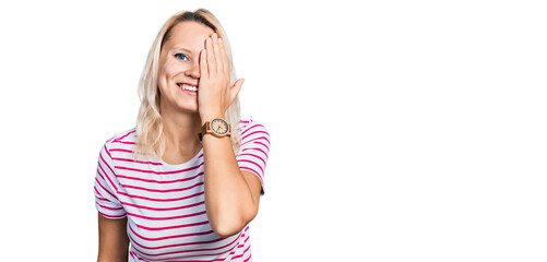 Fototapeta premium Young caucasian woman wearing casual clothes covering one eye with hand, confident smile on face and surprise emotion.