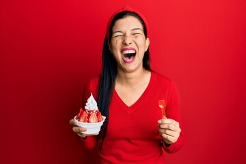 Young latin woman holding ice cream smiling and laughing hard out loud because funny crazy joke.