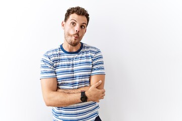 Handsome young man standing over isolated background making fish face with lips, crazy and comical gesture. funny expression.