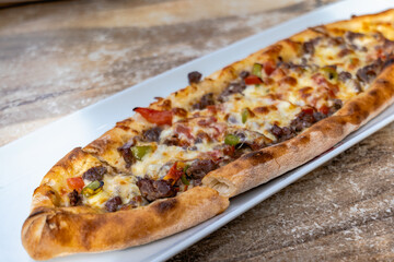 Pide, Turkish bread with meat and cheese topping, close up. Traditional Turkish cuisine on plate close-up