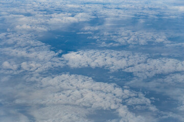 Fototapeta premium Stratosphere, a view of clouds from an airplane window. Cumuliform cloudscape on sky. Flying over the land.