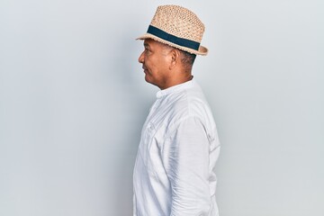 Middle age latin man wearing casual clothes and hat looking to side, relax profile pose with natural face with confident smile.