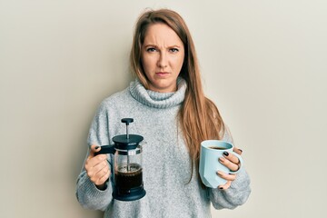 Young blonde woman drinking a cup of italian coffee skeptic and nervous, frowning upset because of problem. negative person.