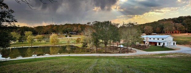 Aerial view of country home ranch with pond and trees at sunset - obrazy, fototapety, plakaty