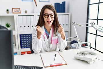 Obraz na płótnie Canvas Young doctor woman wearing doctor uniform and stethoscope at the clinic excited for success with arms raised and eyes closed celebrating victory smiling. winner concept.