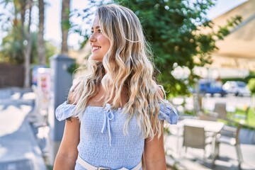 Young blonde girl smiling happy standing at the cityl