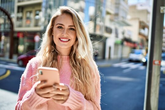 Young blonde woman using smartphone at the city