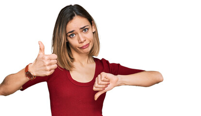 Fototapeta premium Young blonde girl wearing casual clothes doing thumbs up and down, disagreement and agreement expression. crazy conflict