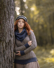 Cozy portrait of a girl in a warm sweater in the autumn forest