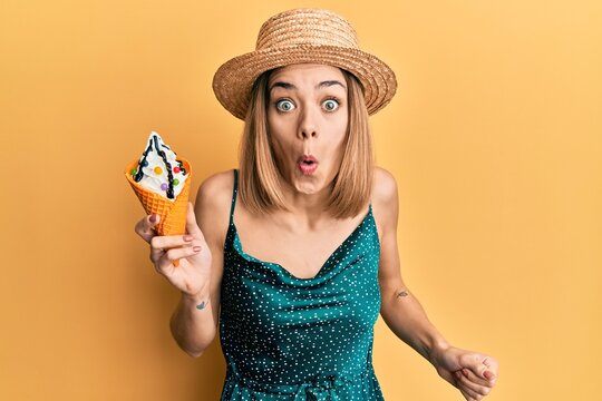 Young caucasian blonde woman eating ice cream scared and amazed with open mouth for surprise, disbelief face