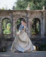 Girl in medieval dress against the background of ancient arches