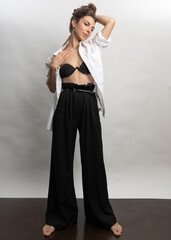 Fototapeta premium Model, brunette posing on a white background in the studio. She is wearing a white shirt, a black hairstyle. Photo to the waist