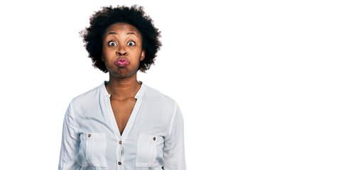 African american woman with afro hair wearing casual white t shirt puffing cheeks with funny face. mouth inflated with air, crazy expression. - obrazy, fototapety, plakaty