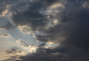 Sunbeams piercing the clouds at dawn.