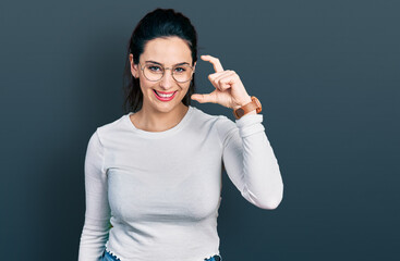 Fototapeta premium Young hispanic woman wearing casual clothes smiling and confident gesturing with hand doing small size sign with fingers looking and the camera. measure concept.