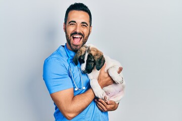 Handsome hispanic veterinary man with beard checking dog health smiling and laughing hard out loud...