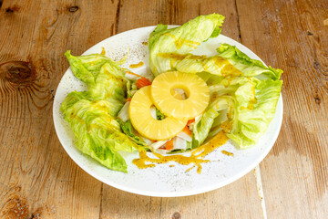 Lettuce and surimi salad with pineapple slices and sweet curry sauce with black pepper