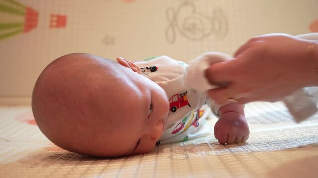 Baby learn head control, 2 month old baby boy lifting head lying on tummy on activity play mat at home.