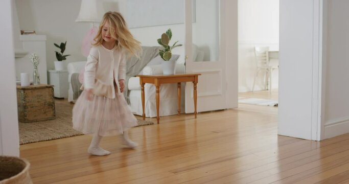 happy little girl dancing playfully with robot vacuum cleaner funny child pretending to be ballerina having fun playing dress up wearing fairy wings ballet costume at home 4k