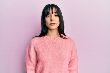 Fototapeta premium Young brunette woman with bangs wearing casual winter sweater relaxed with serious expression on face. simple and natural looking at the camera.
