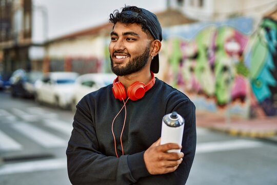 Young arab man smiling confident holding graffiti spray at street