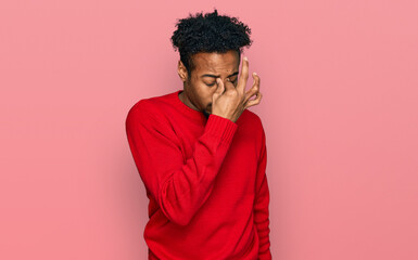 Fototapeta na wymiar Young african american man with beard wearing casual winter sweater tired rubbing nose and eyes feeling fatigue and headache. stress and frustration concept.